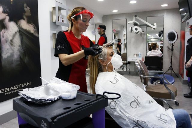 Una peluquera tie el pelo a una clienta durante el estado de alarma