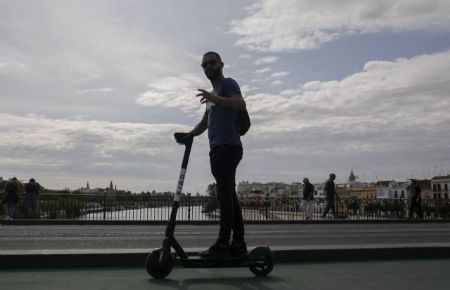 Un joven atraviesa el Puente de Triana de Sevilla con patinete elctrico - Mara Jos Lpez - Europa Press