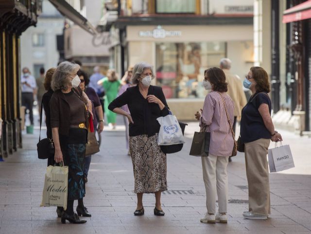 Varias personas protegidas con mascarillas conversan en una calle del centro de la ciudad en Sevilla